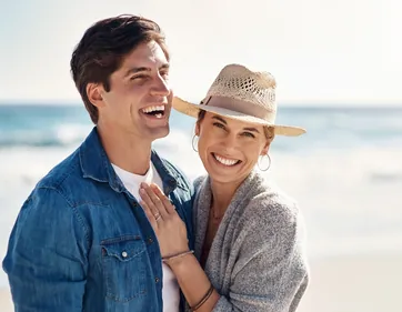 A smiling couple standing together by the coast